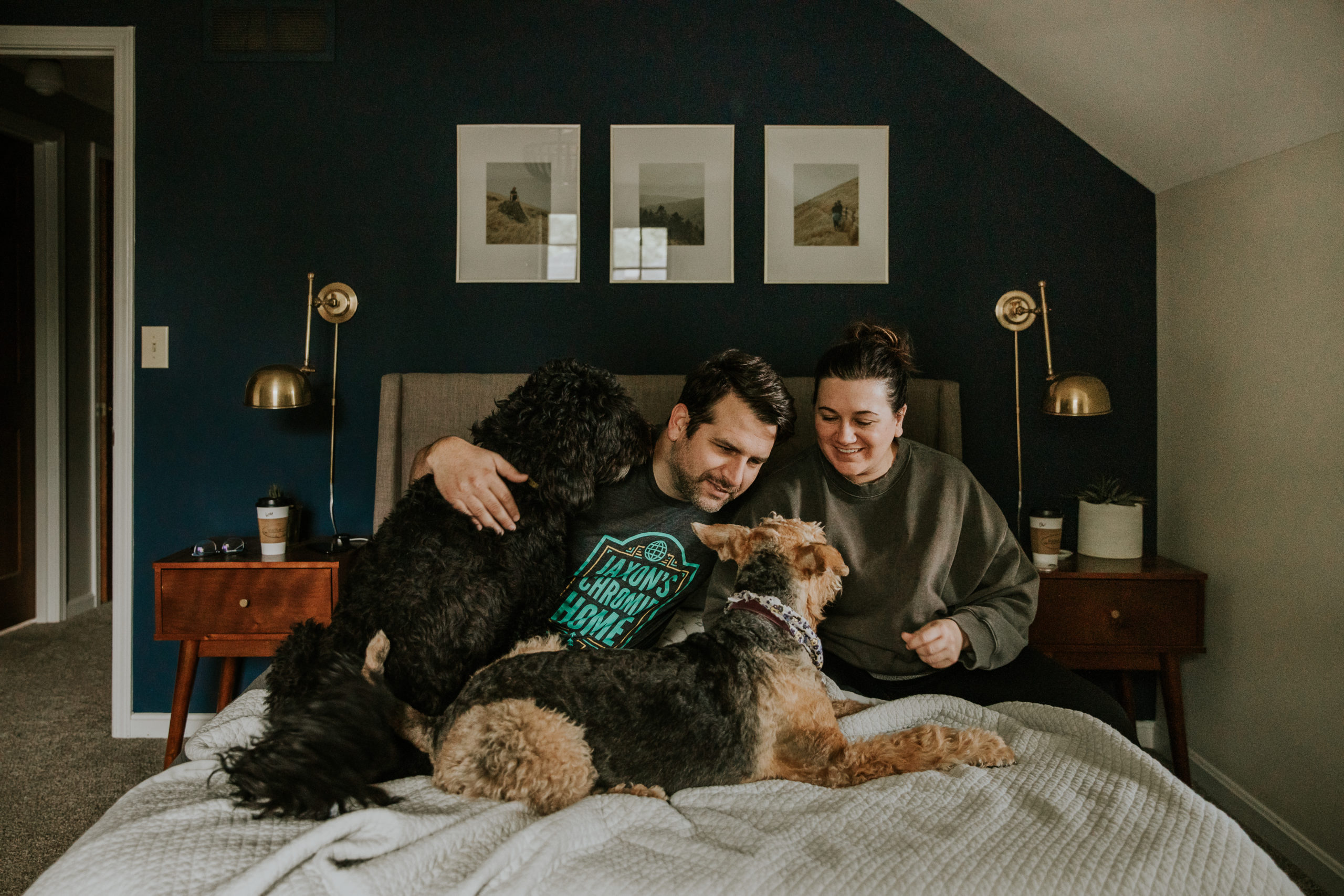 Couple at home relaxing in bed with their two dogs