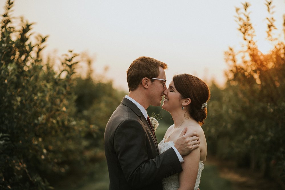 Bride and groom in apple orchard at Hubers Winery at sunset
