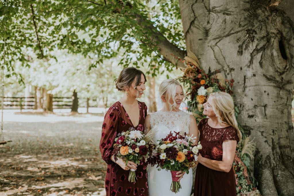 Kentucky bride with her mom and sister under a large tree at a summer wedding